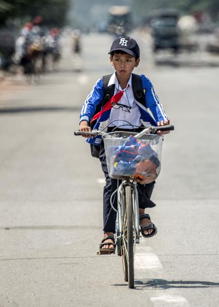 A local boy riding on his bicycle on the way to school