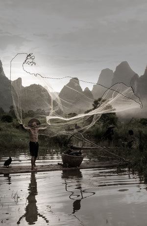 Cormorant fisherman throwing a giant fishing net into the water
